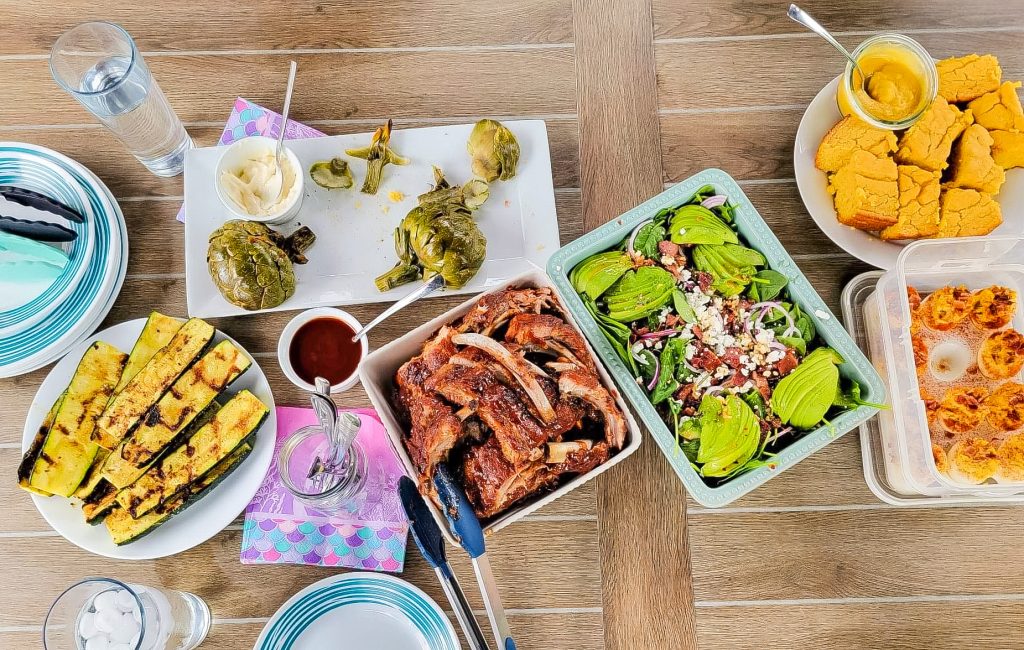 table with grilled zucchini, salad, cornbread, deviled eggs and ribs 