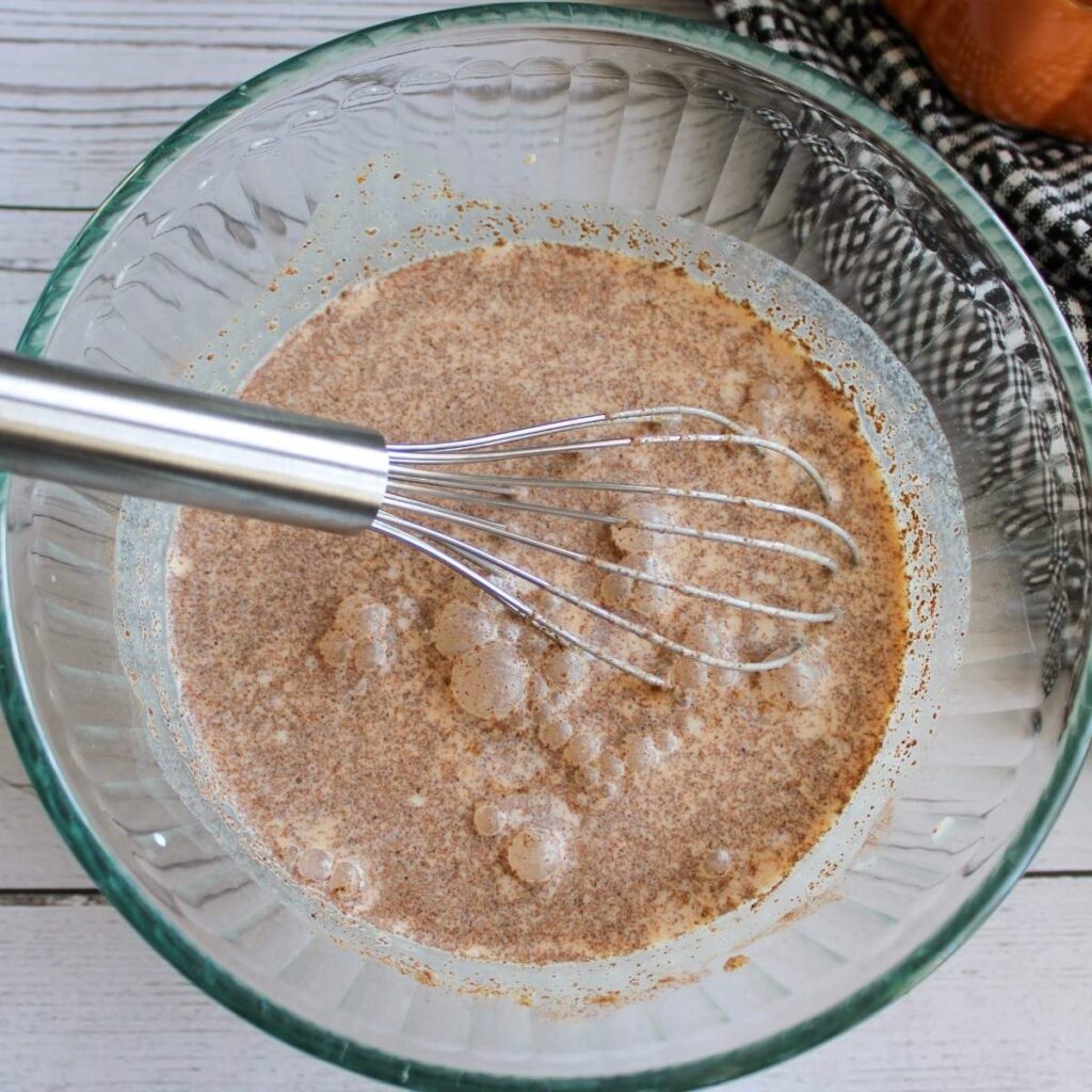 Ingredients for pumpkin spice creamer whisked together in a clear bowl.