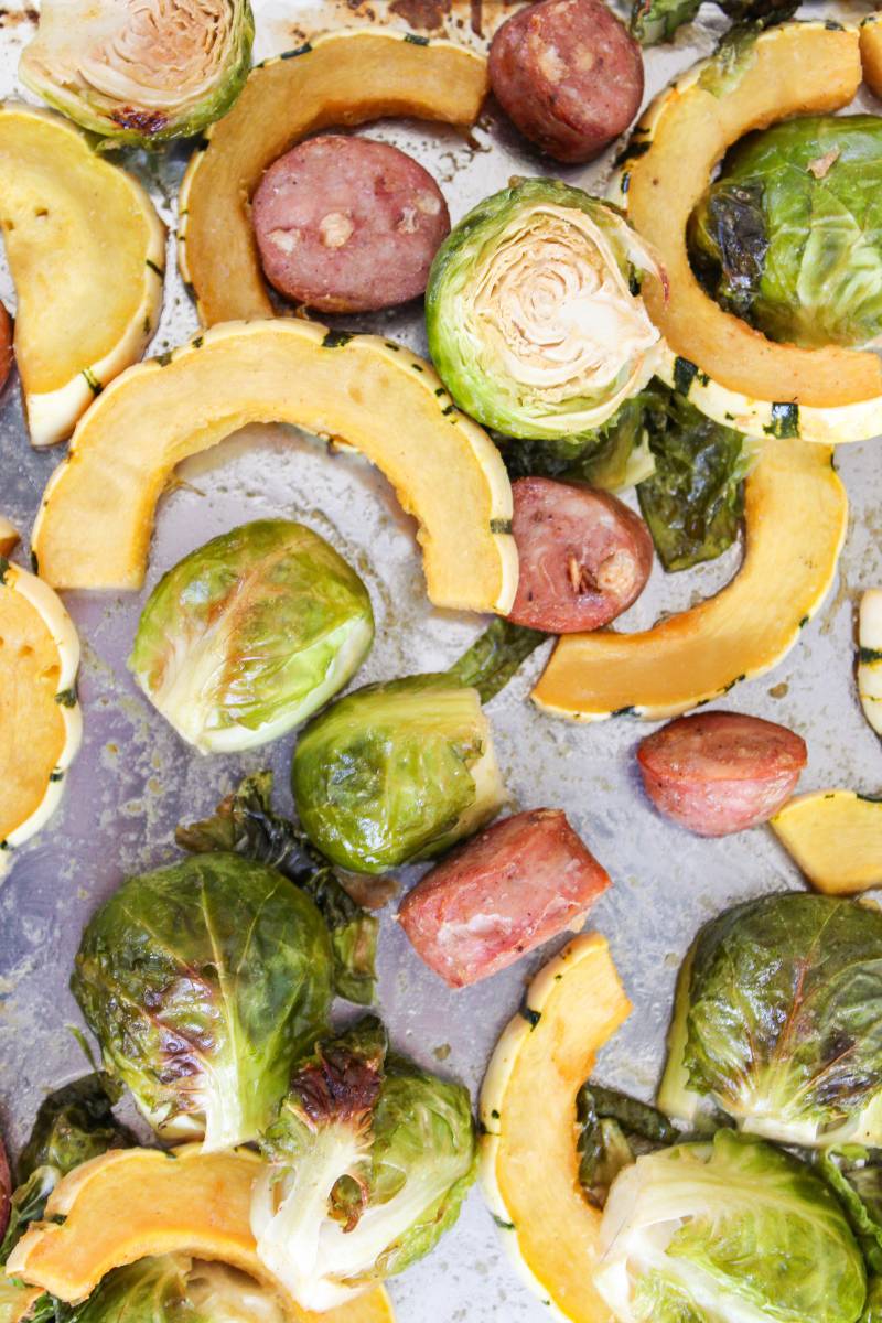 Overhead view of sheet pan with delicata squash. brussels sprouts and apple sausage