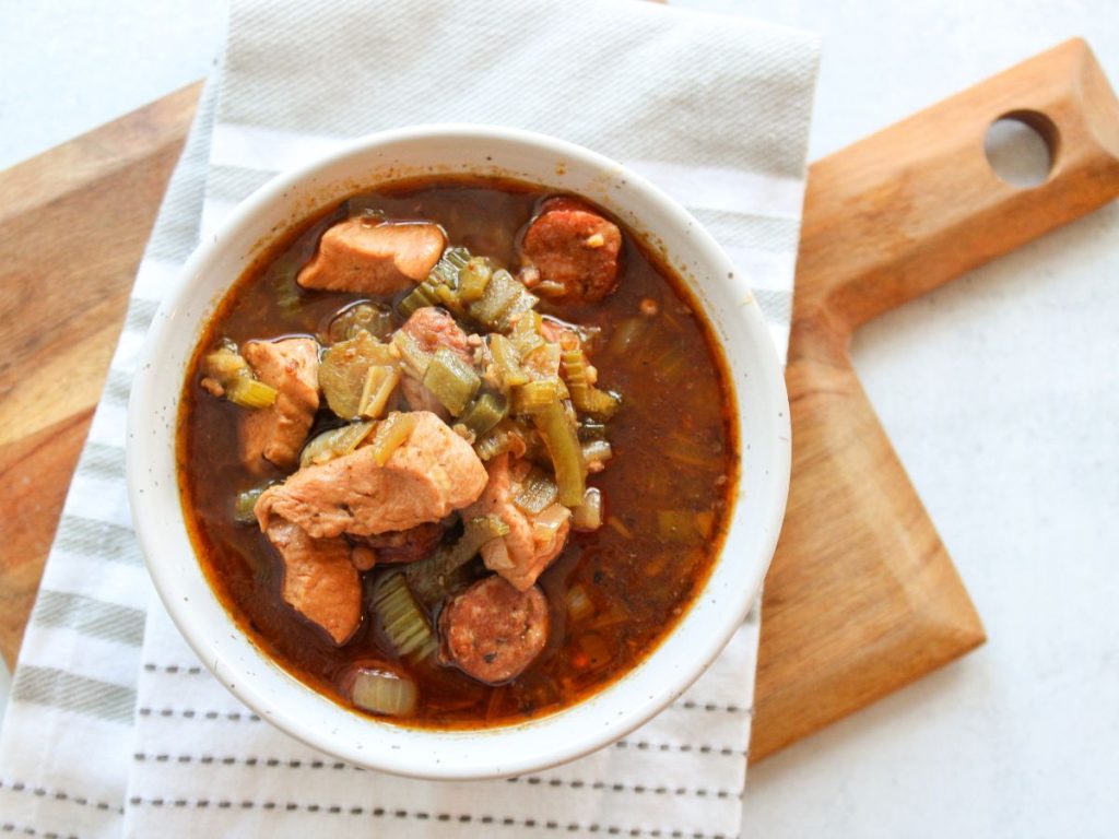 Bowl of gumbo on a cutting board and white and grey towel