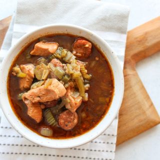 Bowl of gumbo on a cutting board and white and grey towel