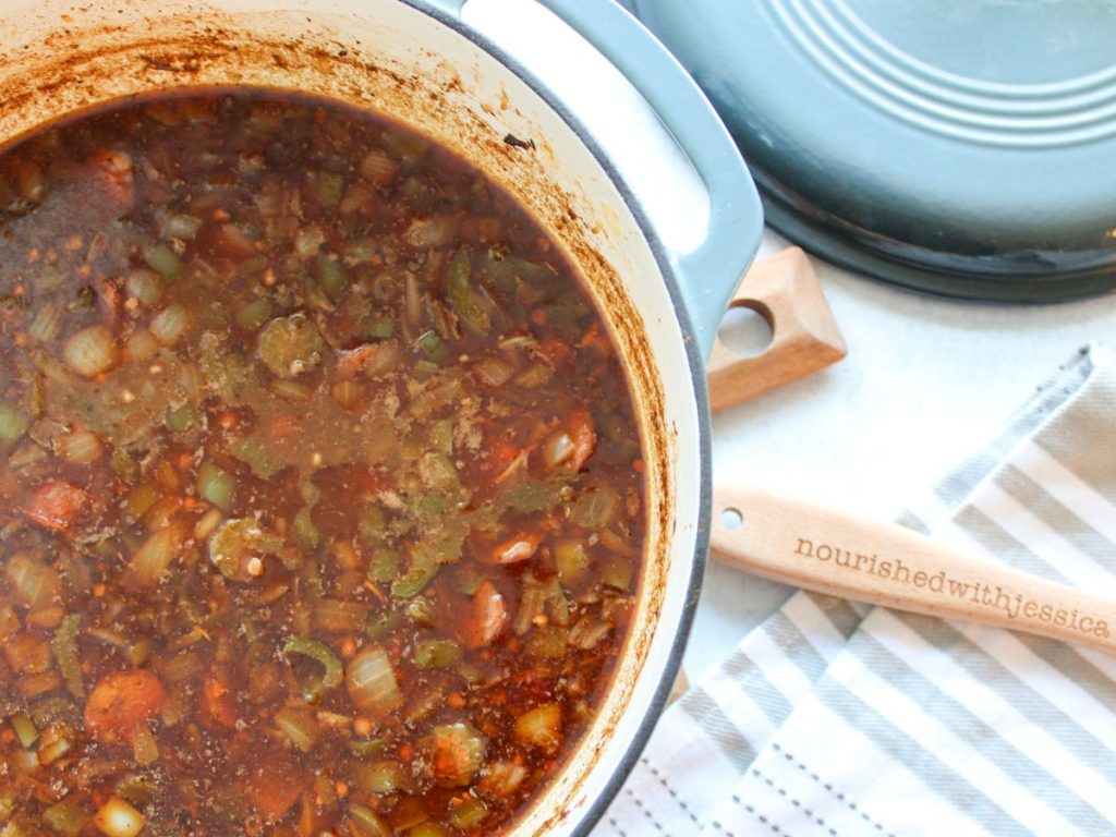 Pot of gumbo in a dutch oven with a wooden spoon next to it