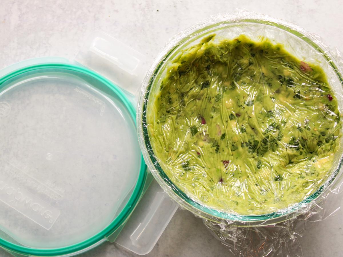 Guacamole in a glass bowl with plastic for storage