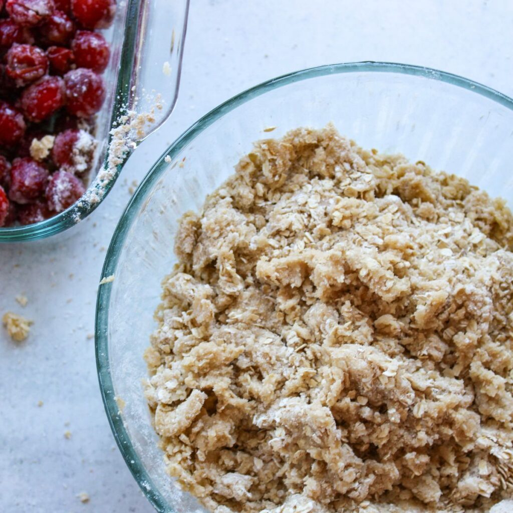 Topping ingredients mixed together for tart cherry crisp in a clear bowl.