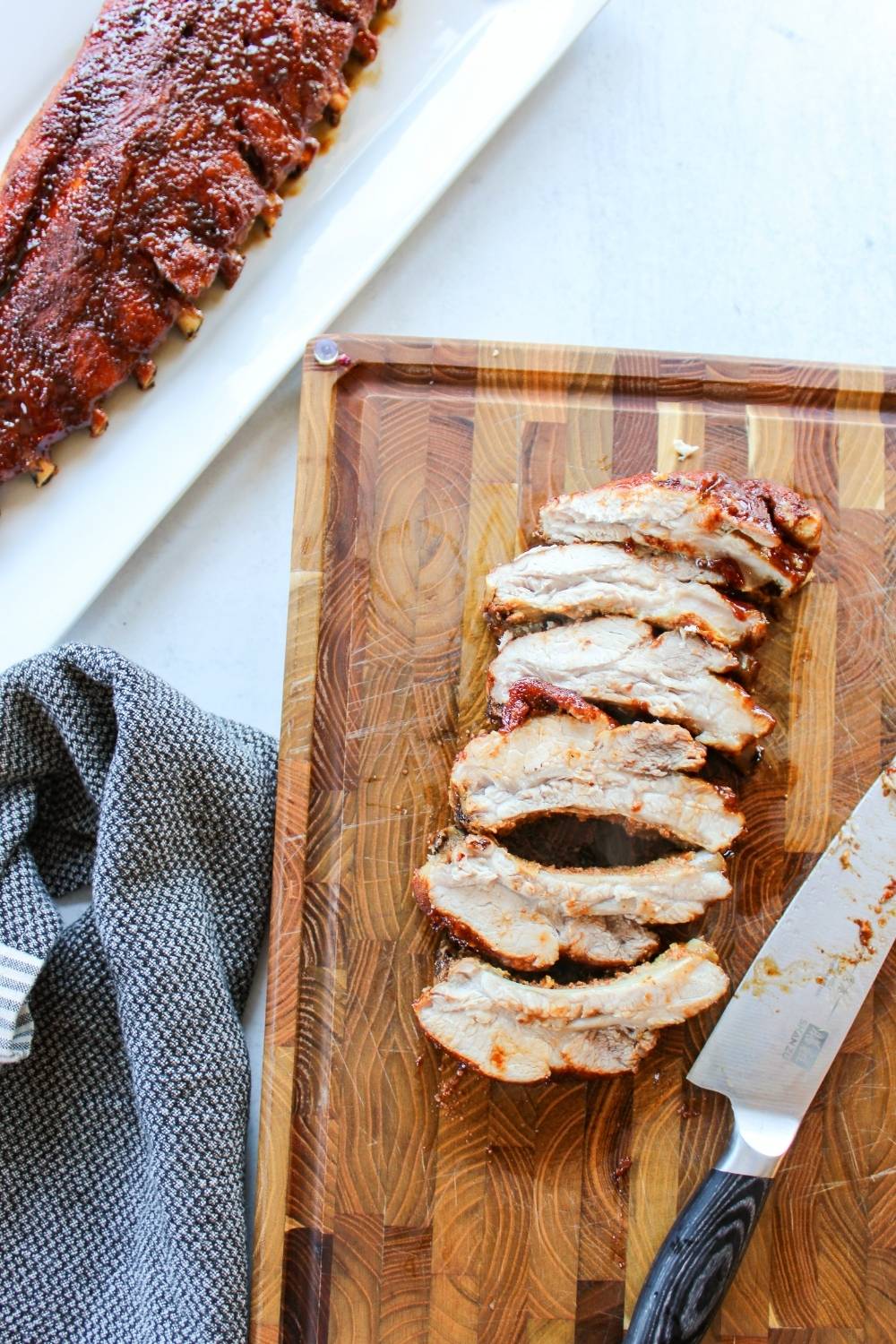 sliced ribs on a cutting board next to a rack of ribs