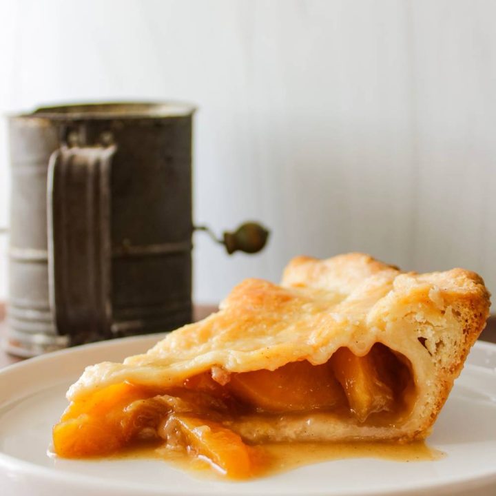 slice of peach pie next to flour sifter