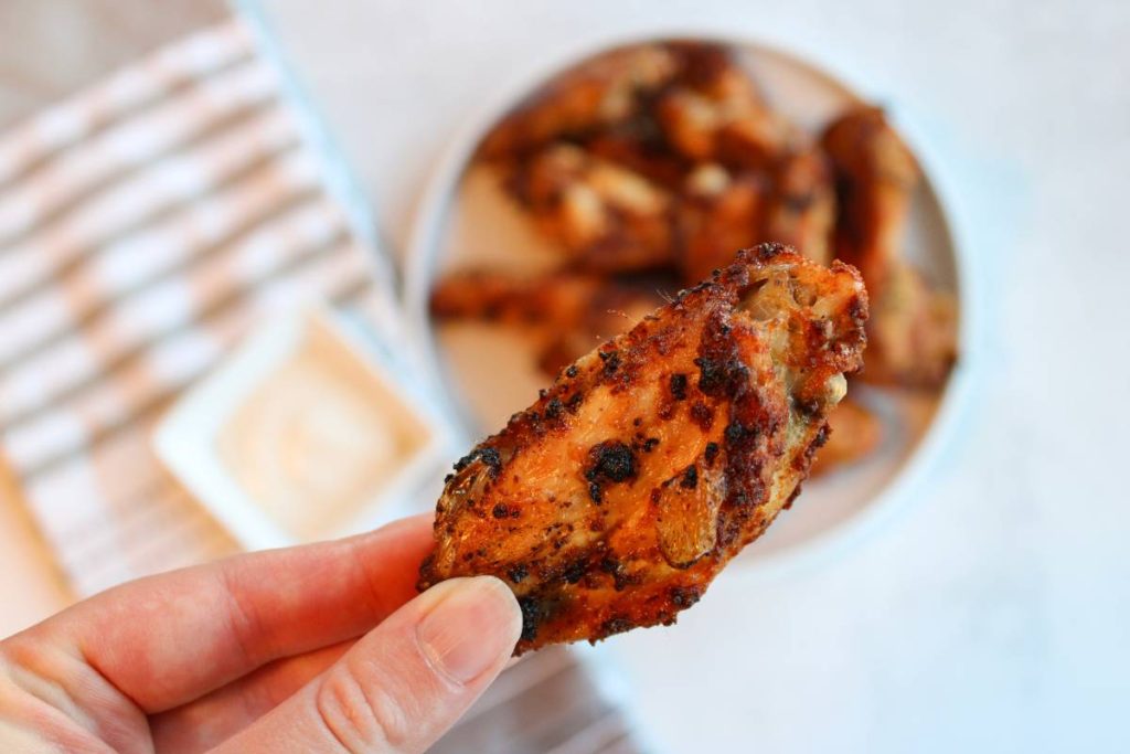 Hand holding dry rub chicken wing