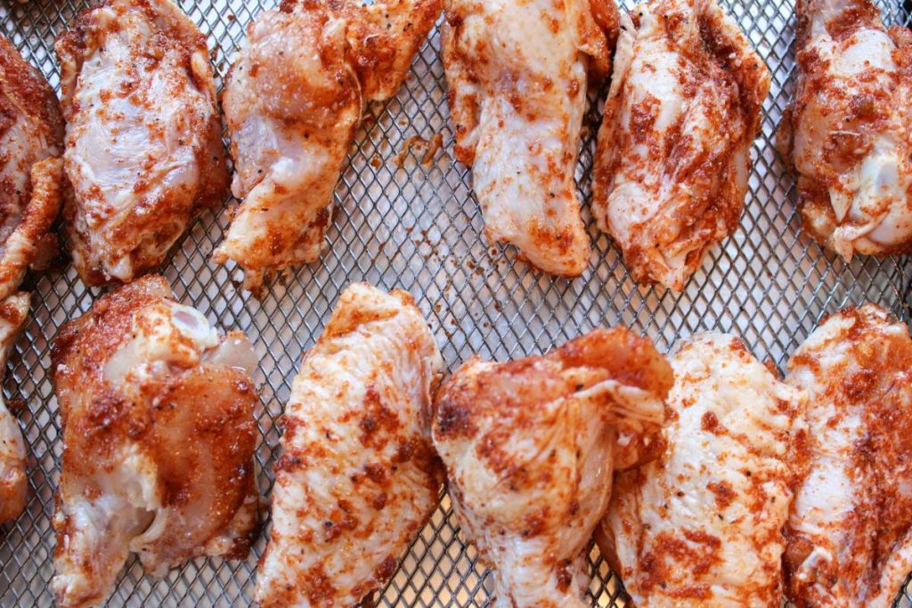 raw wings with dry rub on them on the air fryer tray