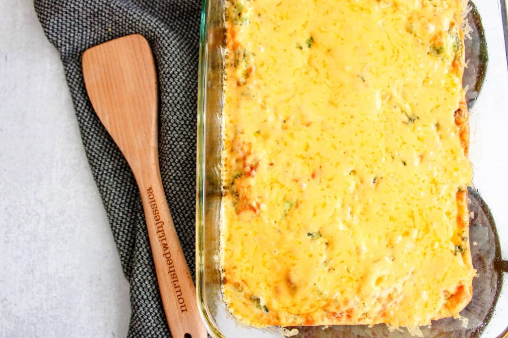 Broccoli and cheddar frittata in a 9x13 pan next to a wooden spoon