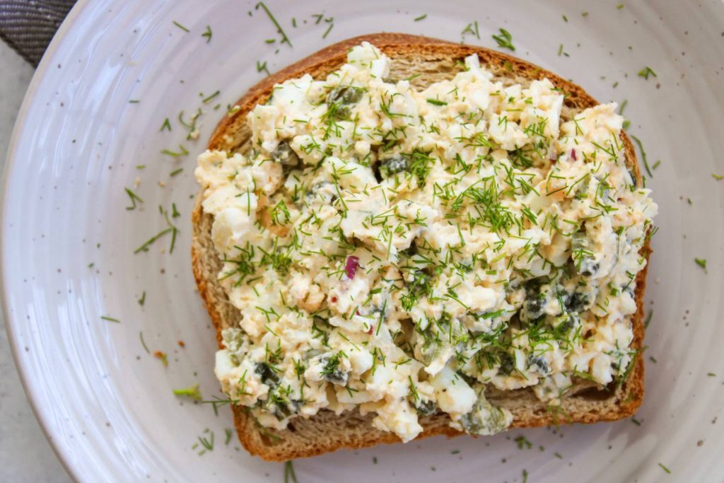 Egg salad on top of a piece of toast with dill sprinkled on top