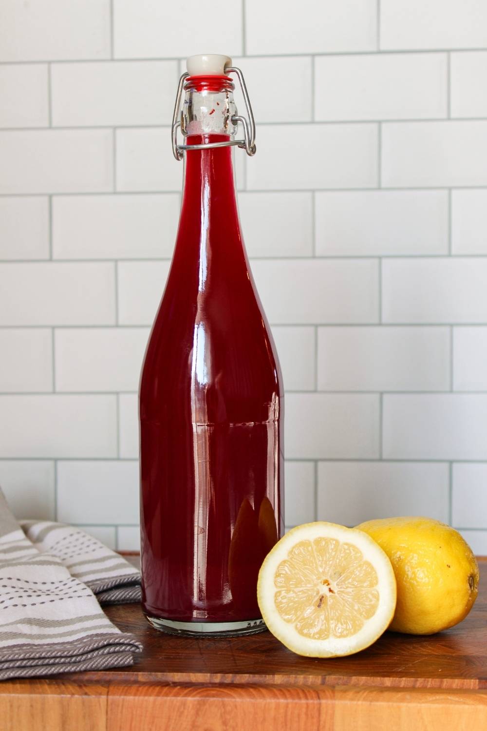 glass bottle filled with blueberry lavender lemonade with lemon next to it