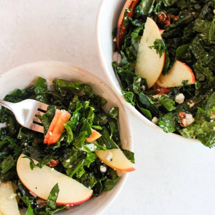 Over head view of kale and apple salad with a bowl next to it