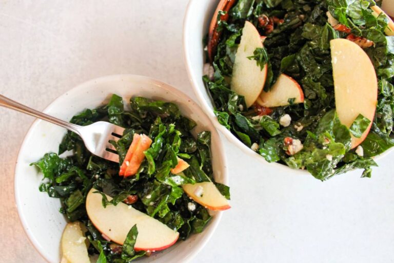 Over head view of kale and apple salad with a bowl next to it