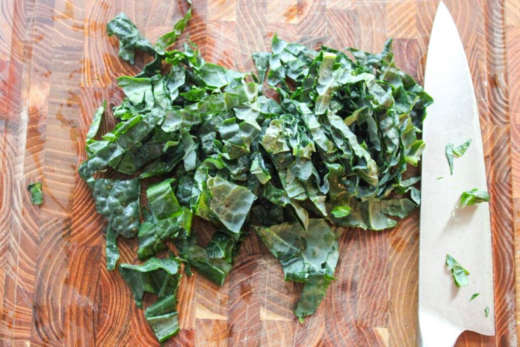 chopped kale on a cutting board next to a knife