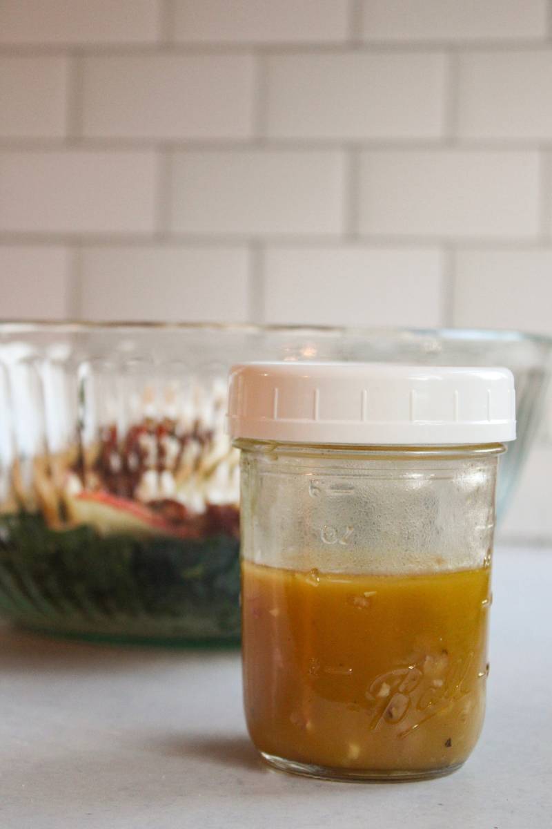 Apple cider vinaigrette next to kale and apple salad