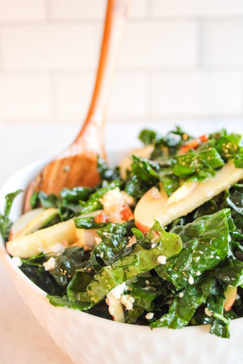 wooden spoon in a bowl of kale and apple salad