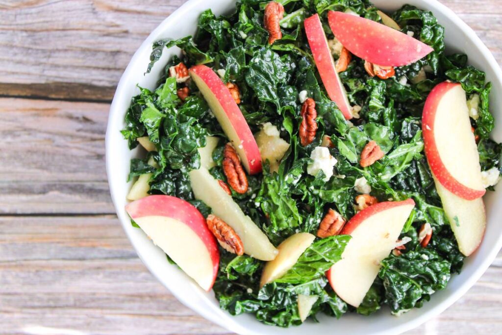 bowl of kale and apple salad with candied pecans