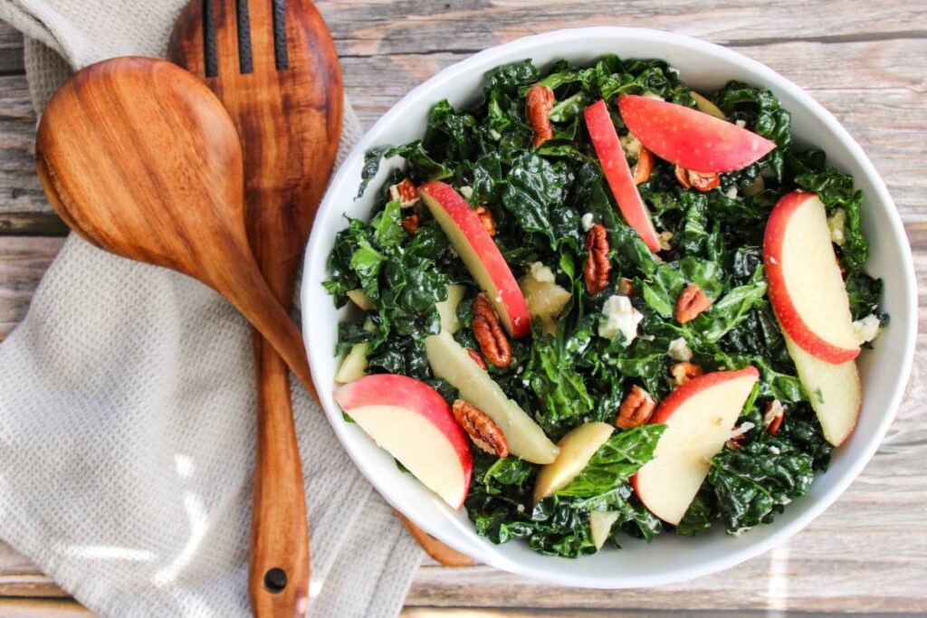 white bowl of kale and apple salad with salad fork and spoon