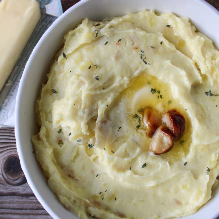 Bowl of mashed potatoes with a stick of butter next to it