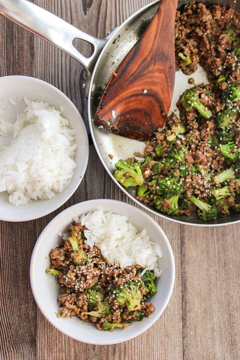 Bowl with beef and broccoli next to skillet and rice