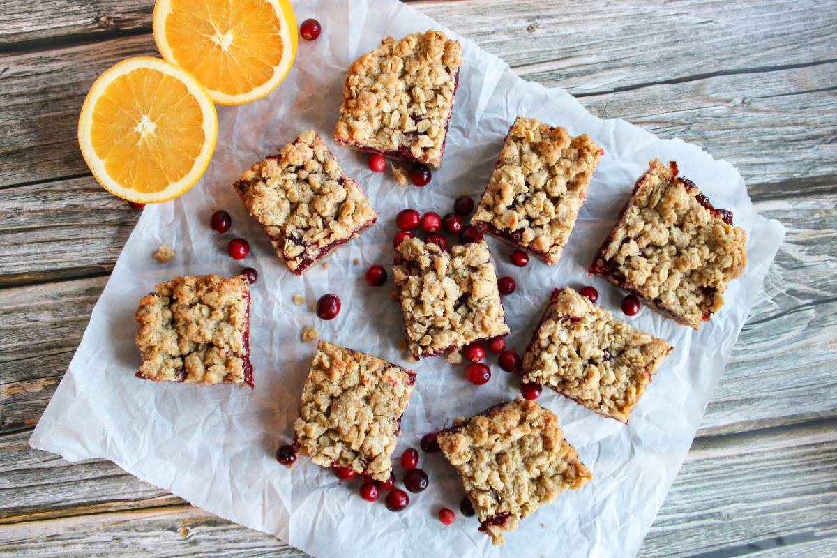 overhead view of cranberry orange oat bars next to half a fresh orange and fresh cranberries