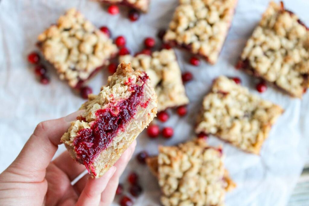 hand holding cranberry orange bars to expose filling