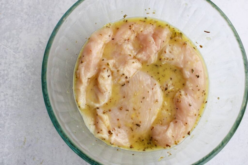 chicken with marinade in a glass bowl