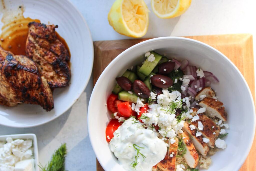 Greek Chicken Quinoa Bowls next to the plate of lemon chicken