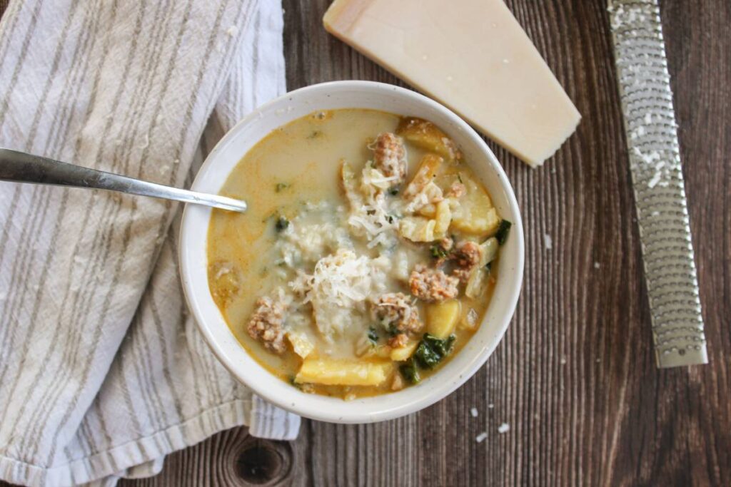 Zuppa Toscana Soup next to parmesan cheese and grater