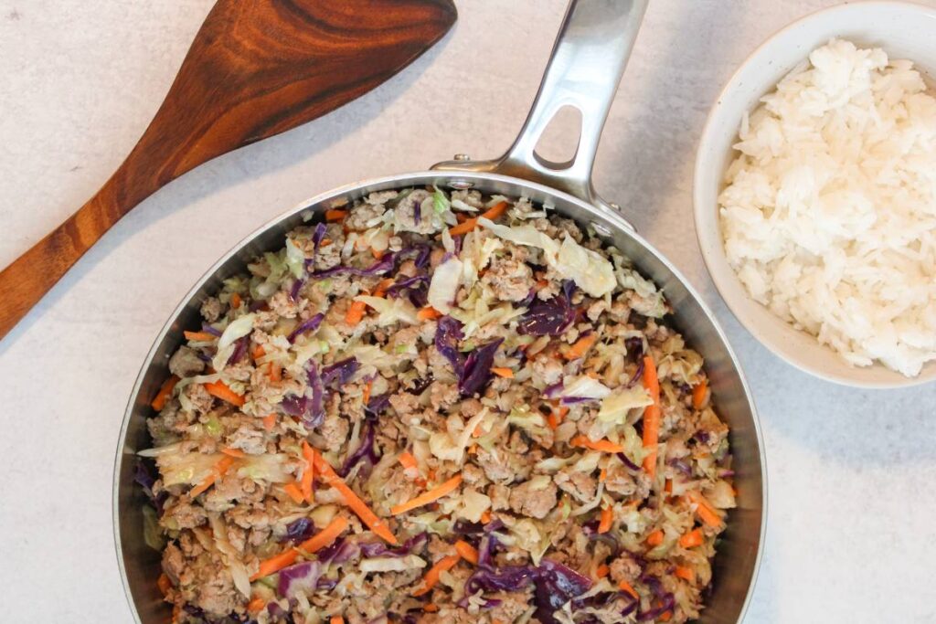 skillet with egg roll in a bowl next to a bowl of rice