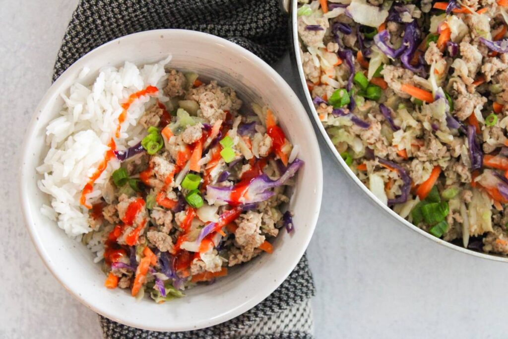 overhead view of egg roll in a bowl with a drizzle of sriracha