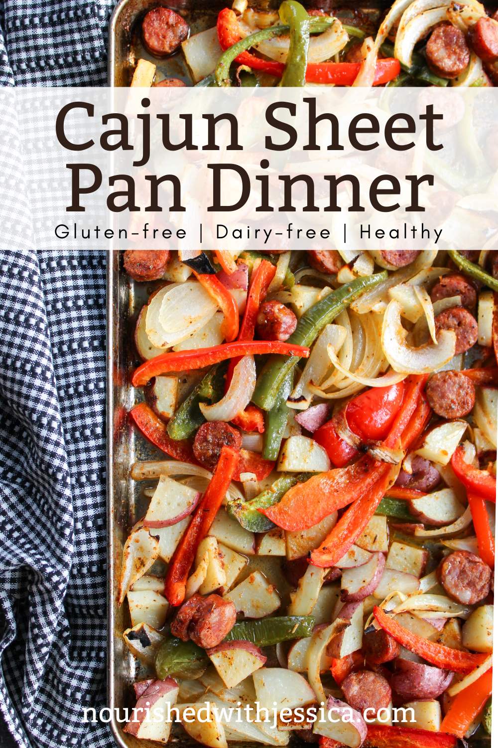 Cajun Sheet Pan dinner filled with Cajun Sausage, Potato and Vegetables next to a black and white cloth towel.