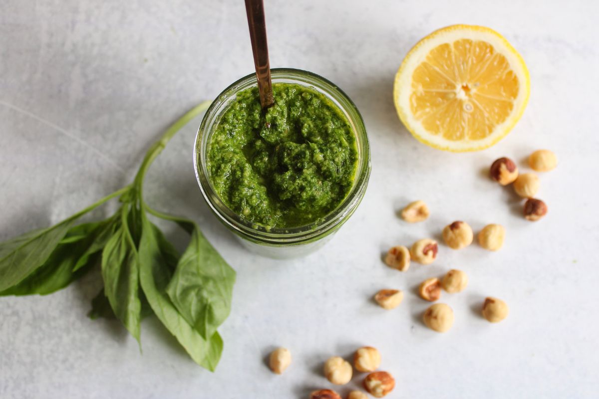 overhead view of dairy free hazelnut pesto next to a lemon, hazelnuts and a lemon wedge. 