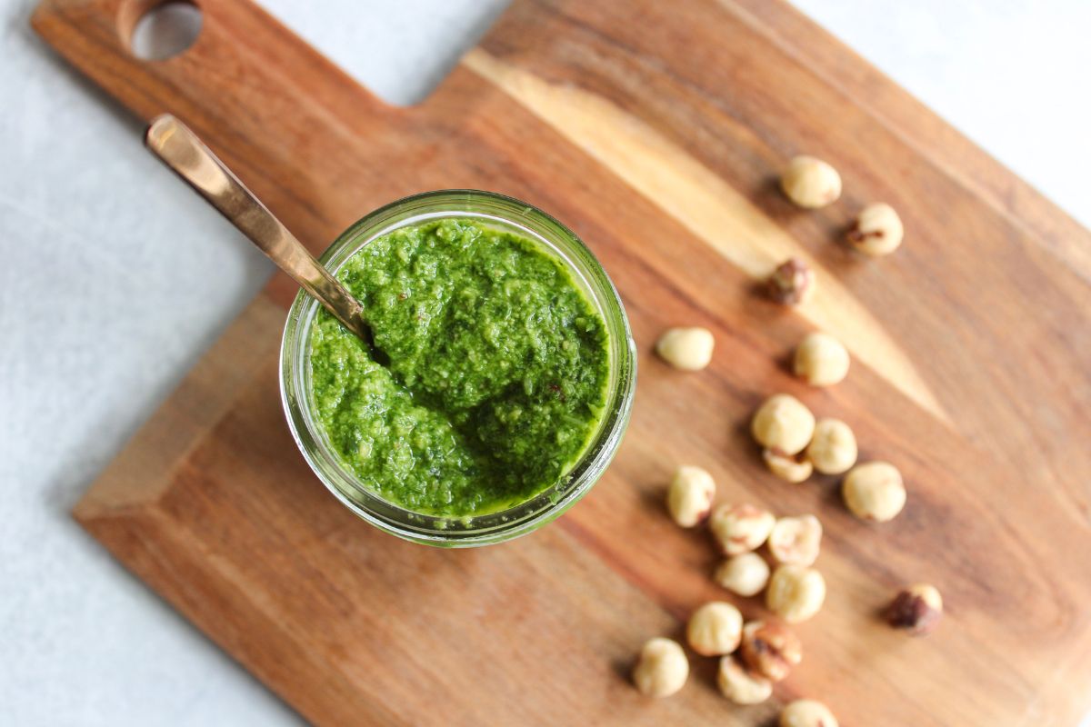 overhead view of hazelnut pesto on a wood board next to hazelnuts