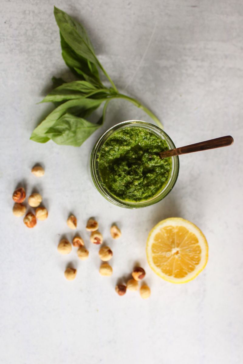 overhead view of dairy free hazelnut pesto next to a lemon, hazelnuts and a lemon wedge.