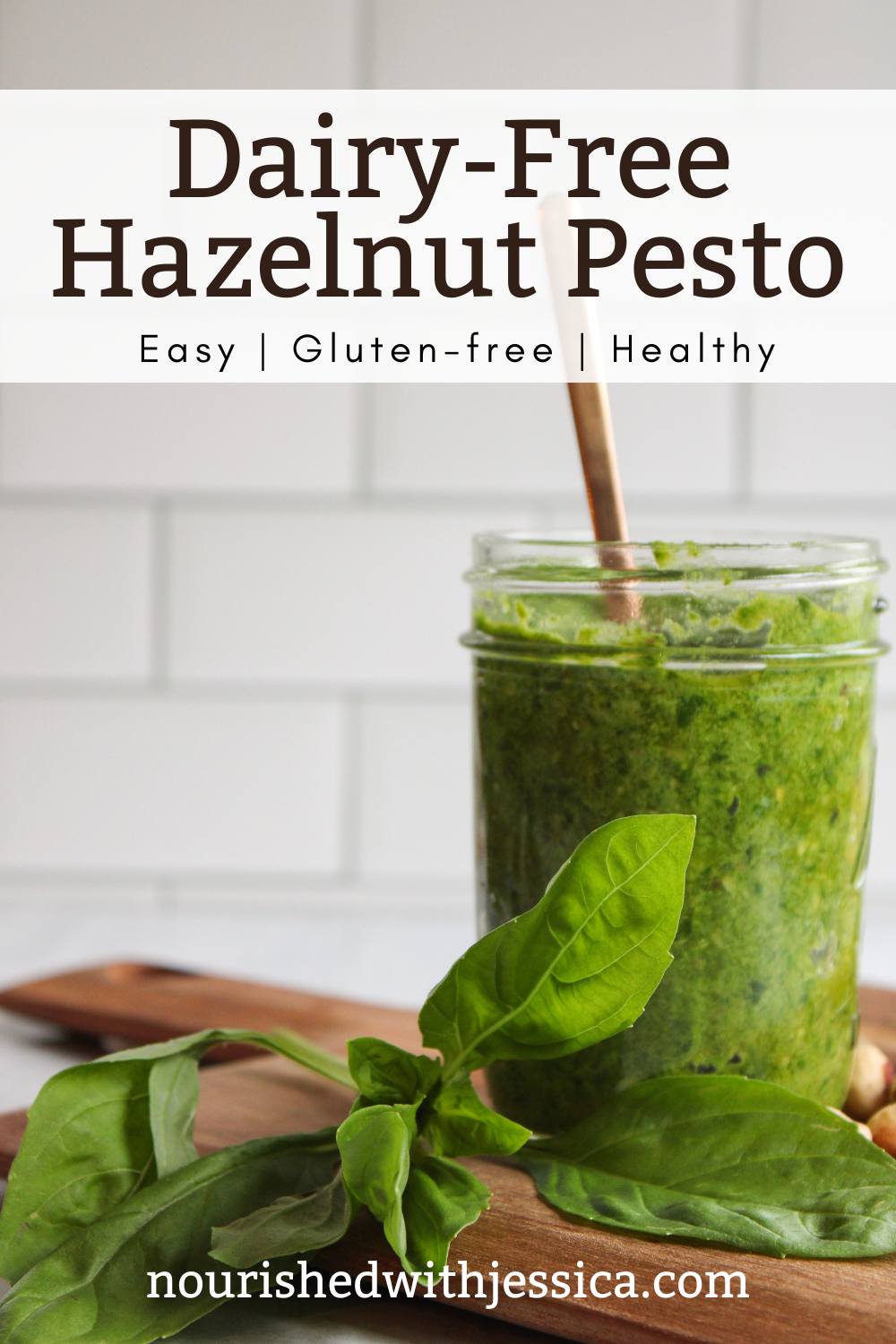 Hazelnut pesto on a wooden cutting board next to basil leaves