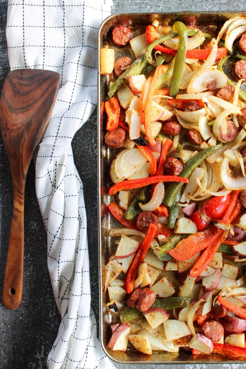 Cajun sheet pan dinner next to a wooden spatula and white cloth napkin