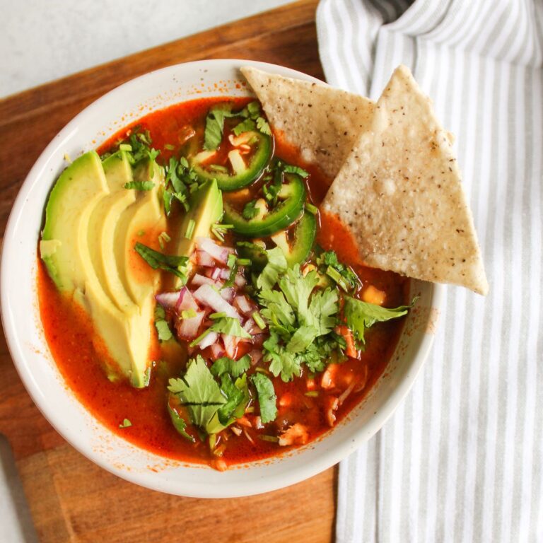 bowl of chicken tortilla soup with chips, avocado, cilantro, red onions and jalapenos