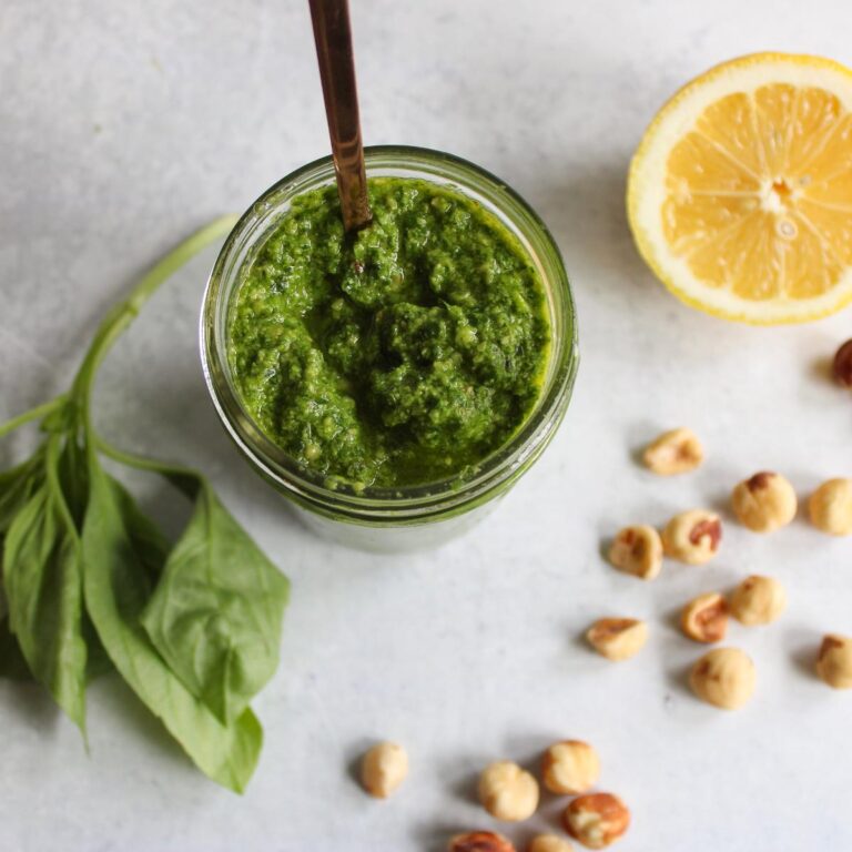 overhead view of dairy free hazelnut pesto next to a lemon, hazelnuts and a lemon wedge.