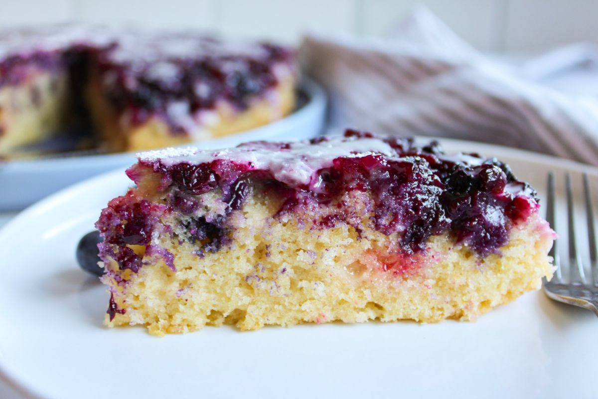 Close up of a slice of Blueberry Upside Down Cake on a white plate.