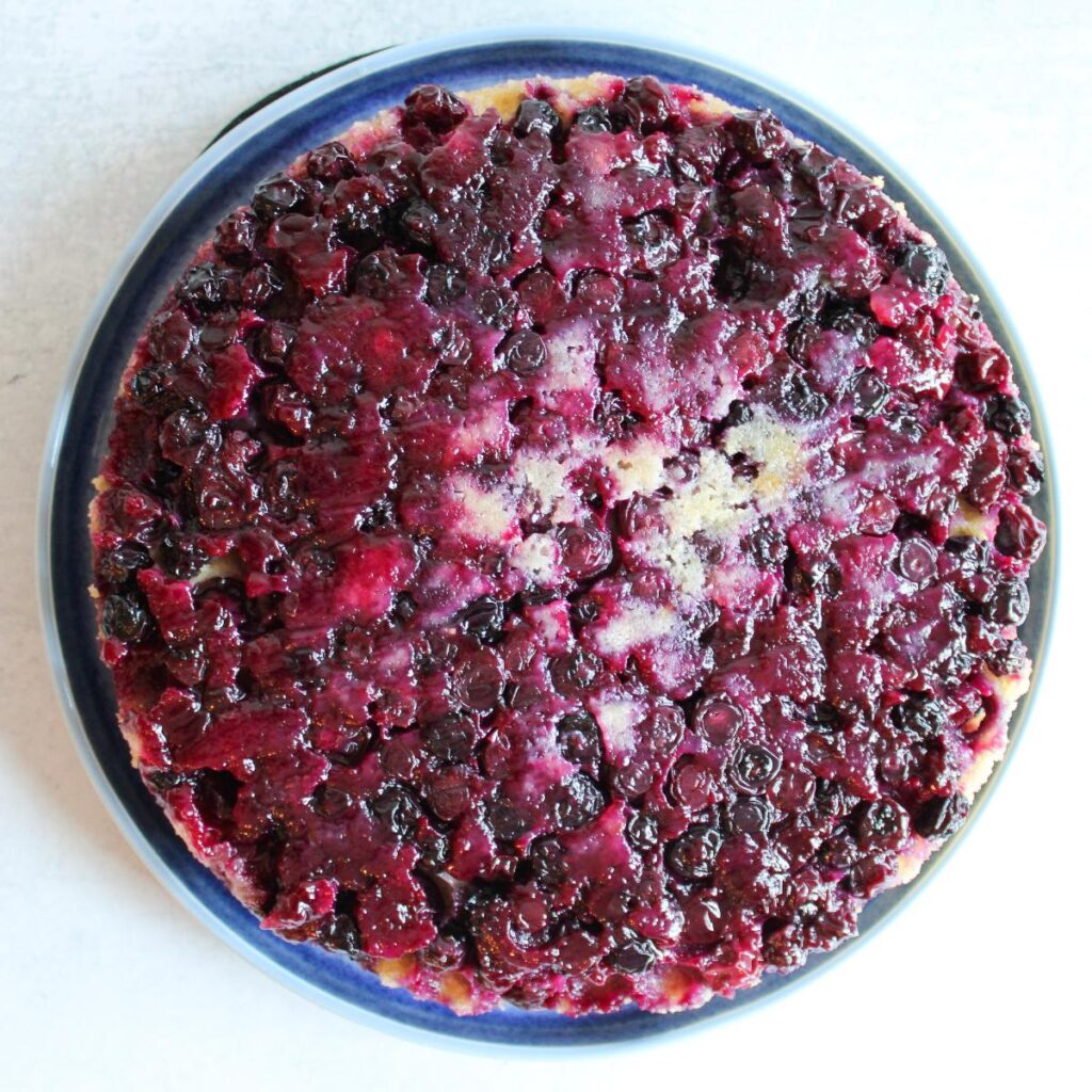 Blueberry Upside Down Cake flipped upside down on a blue plate to reveal the blueberry topping.
