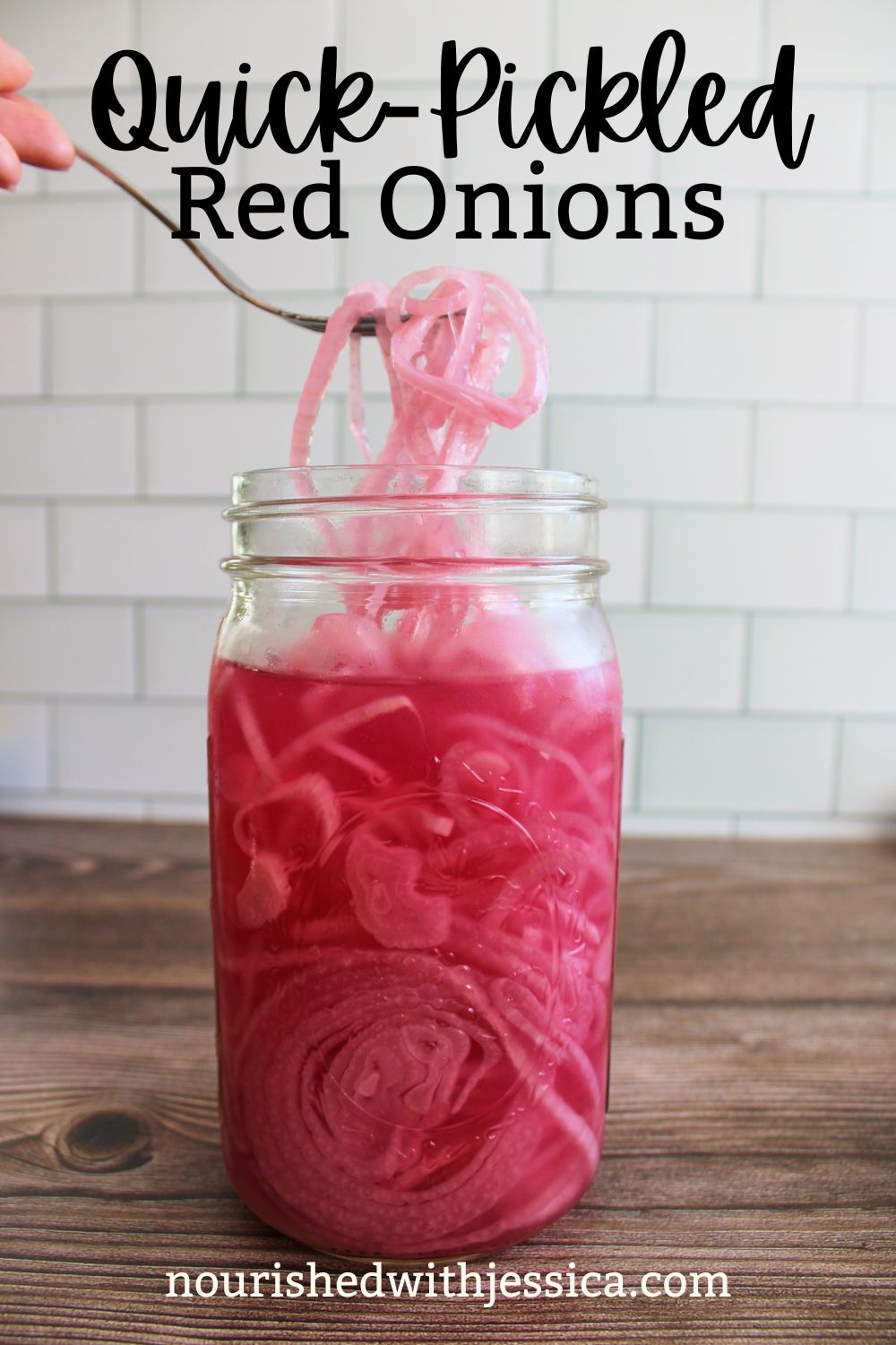 quick-pickled red onions in a quart mason jar with a fork pulling some onions out.