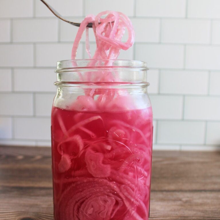 quick-pickled red onions in a quart mason jar with a fork pulling some onions out.
