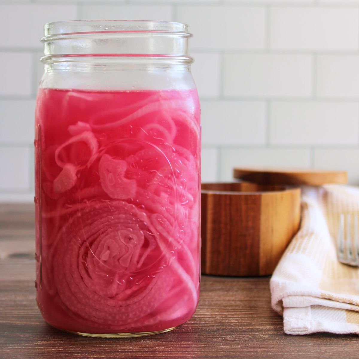 Quick pickled red onions in a mason jar next to a container of salt.