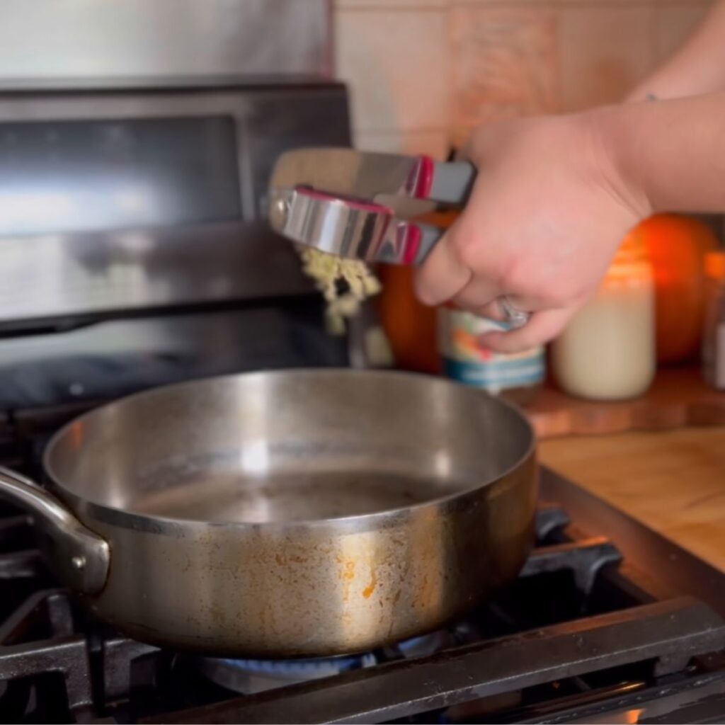Garlic press over a medium saucepan. 