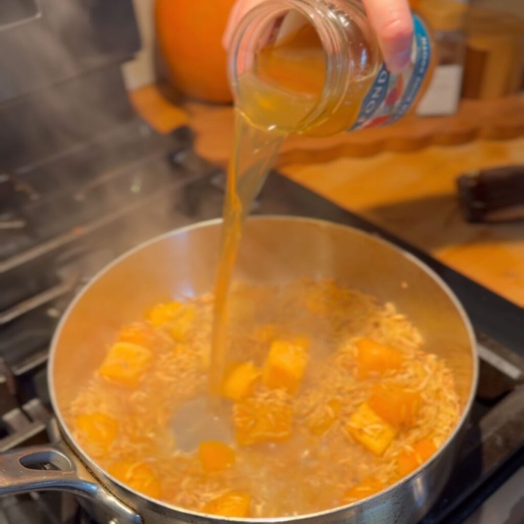 Broth being added to the pan to make creamy orzo.