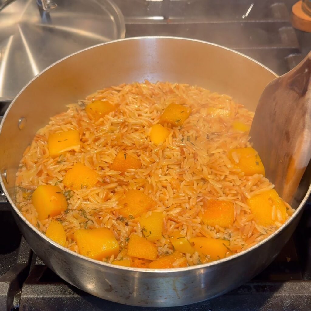 Orzo fully cooked with butternut squash in a medium saucepan.