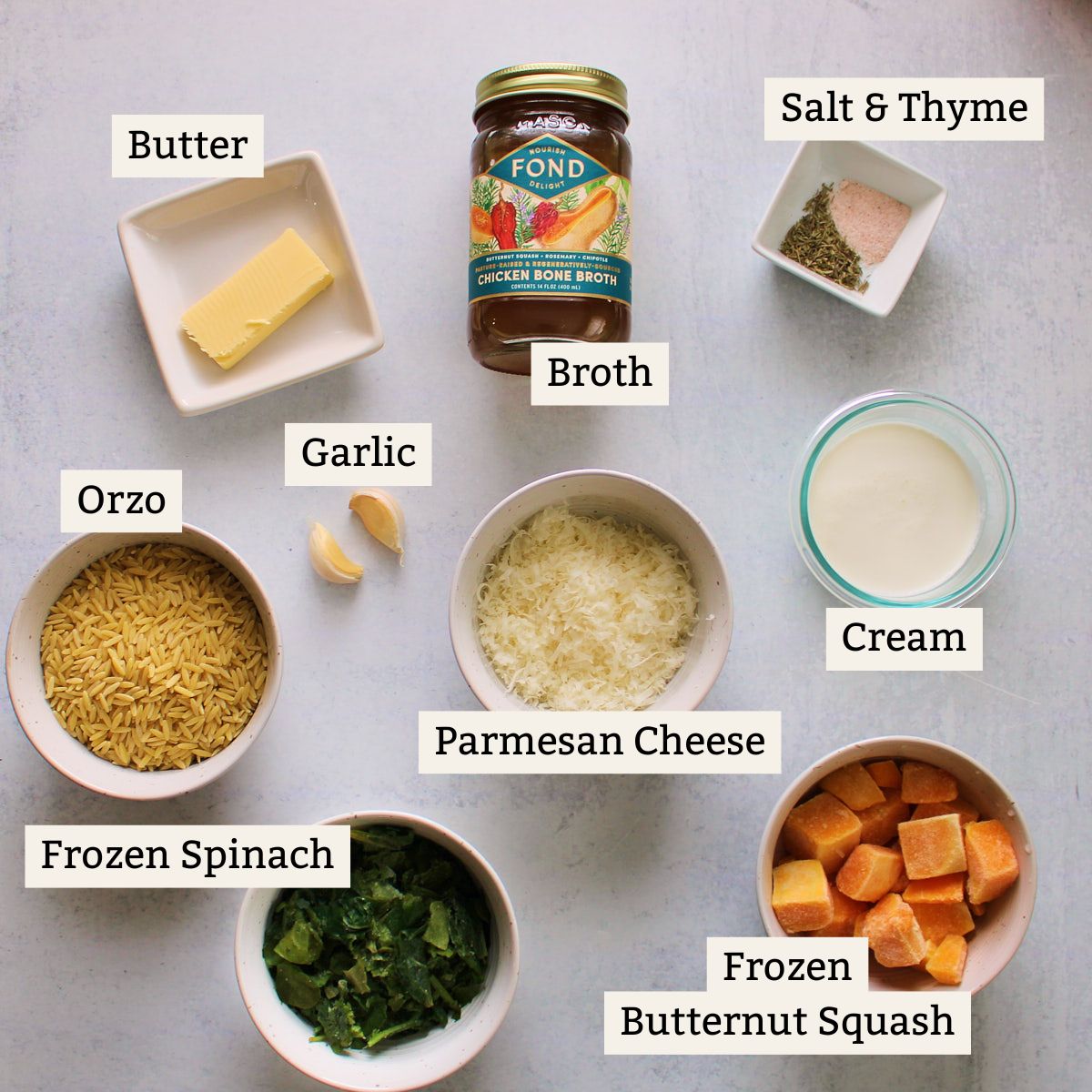 Ingredients for creamy orzo on white background in clear bowls. 